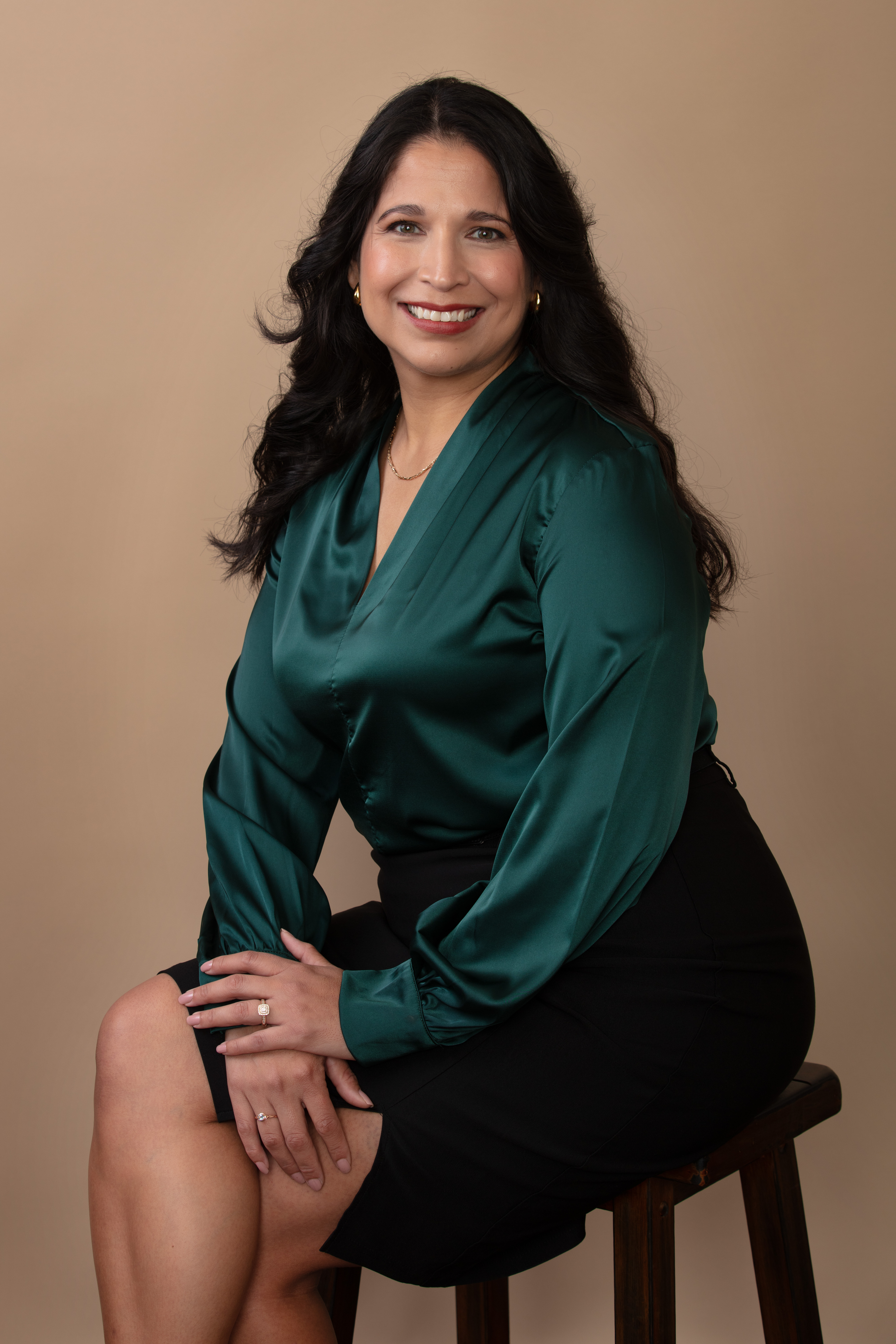 Professional studio headshot, warm tan backdrop